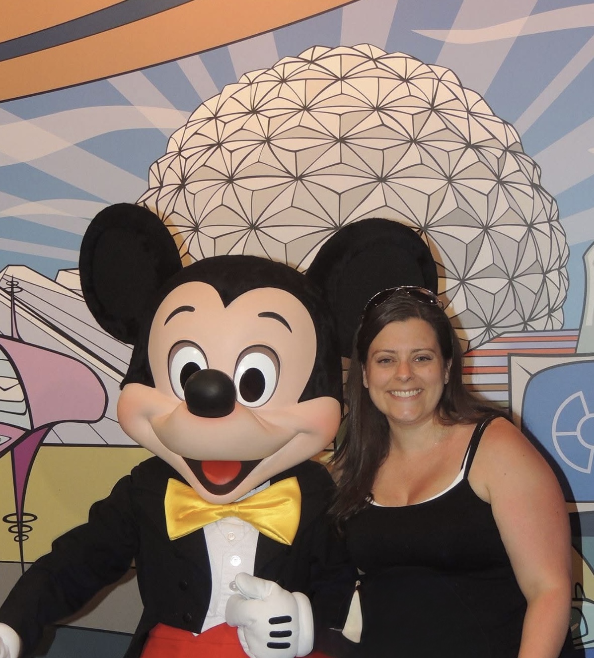 Stephanie with Mickey Mouse in front of Spaceship Earth mural at EPCOT