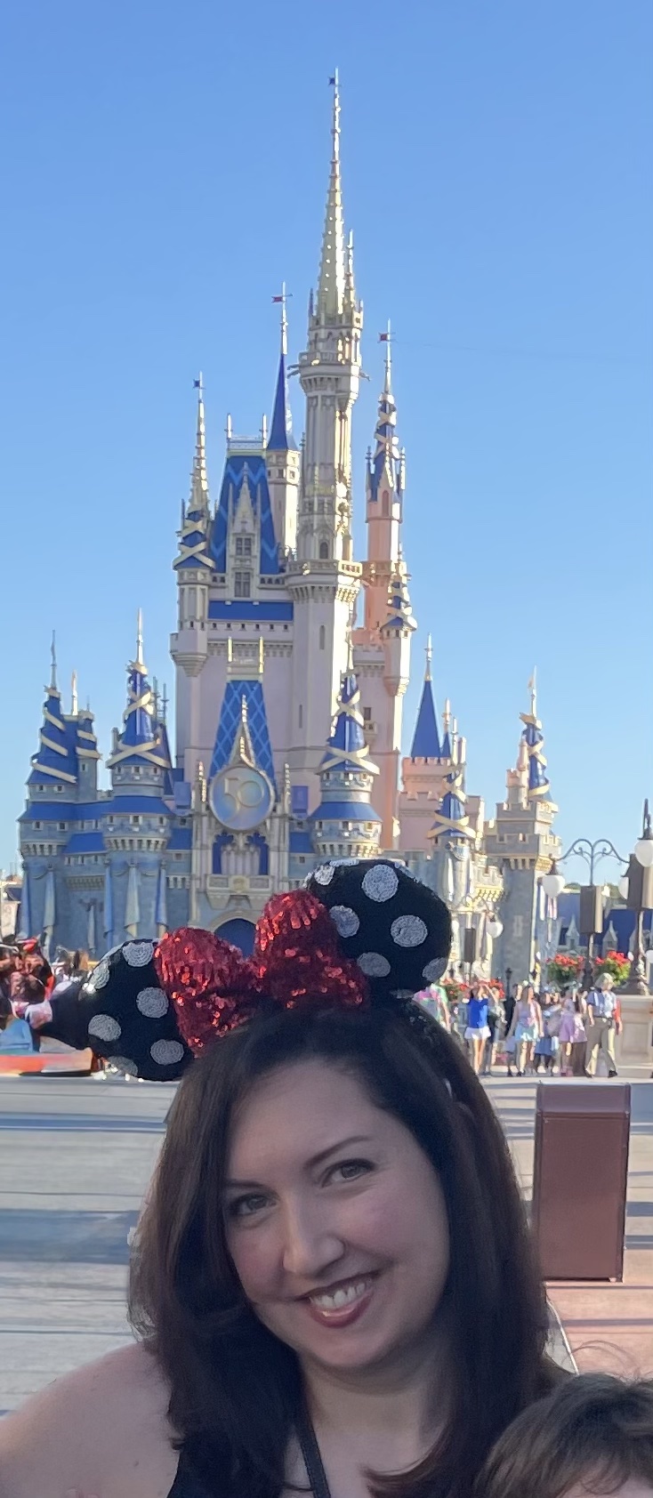 Diana Tombolillo wearing Minnie Mouse ears in front of Cinderella Castle