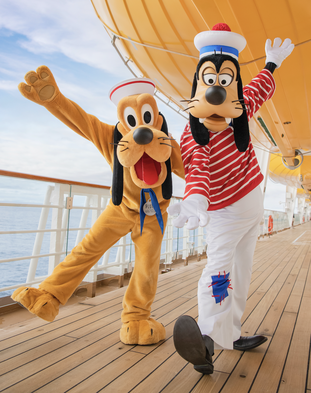 Pluto and Goofy in sailor outfits on the deck of a Disney Cruise Line ship